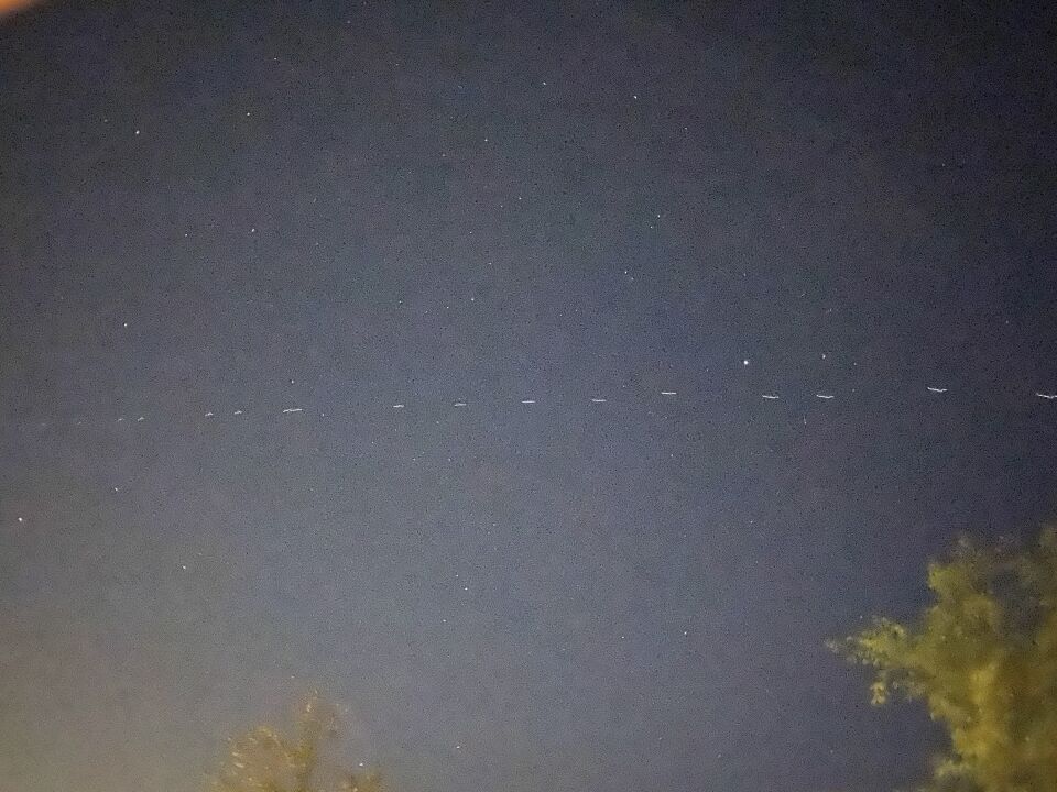 Lange formatie witte lichtjes (70+), ze vliegen richting het Noorden. foto
