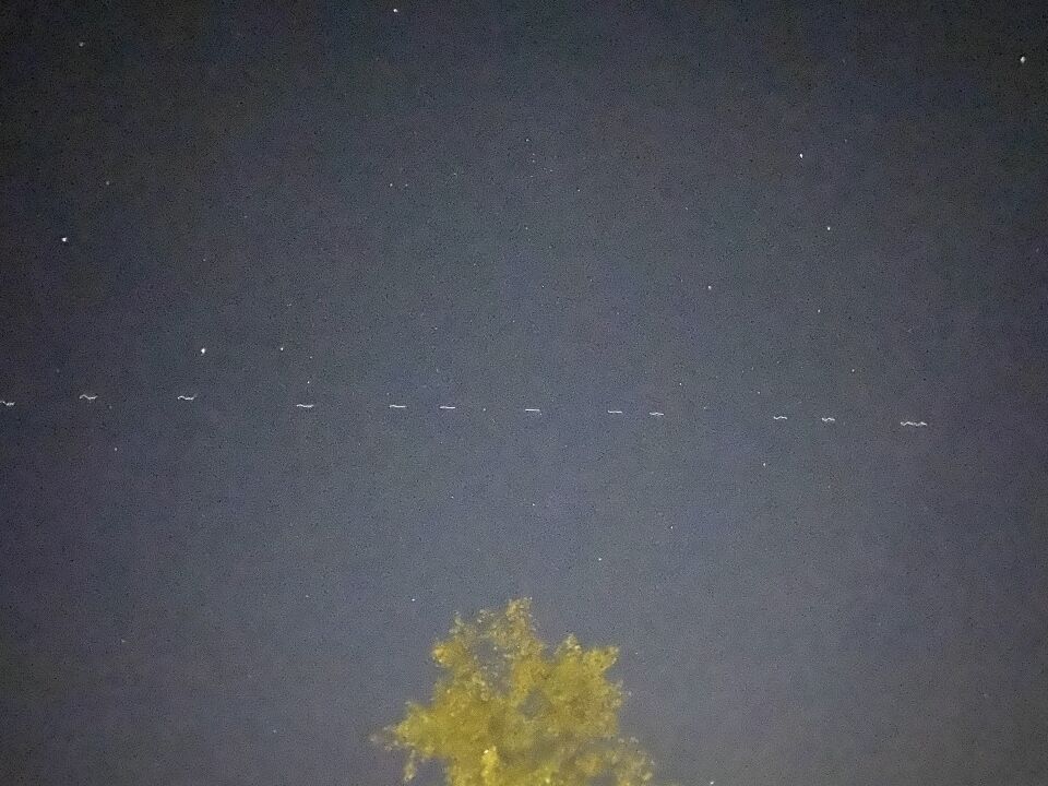 Lange formatie witte lichtjes (70+), ze vliegen richting het Noorden. foto