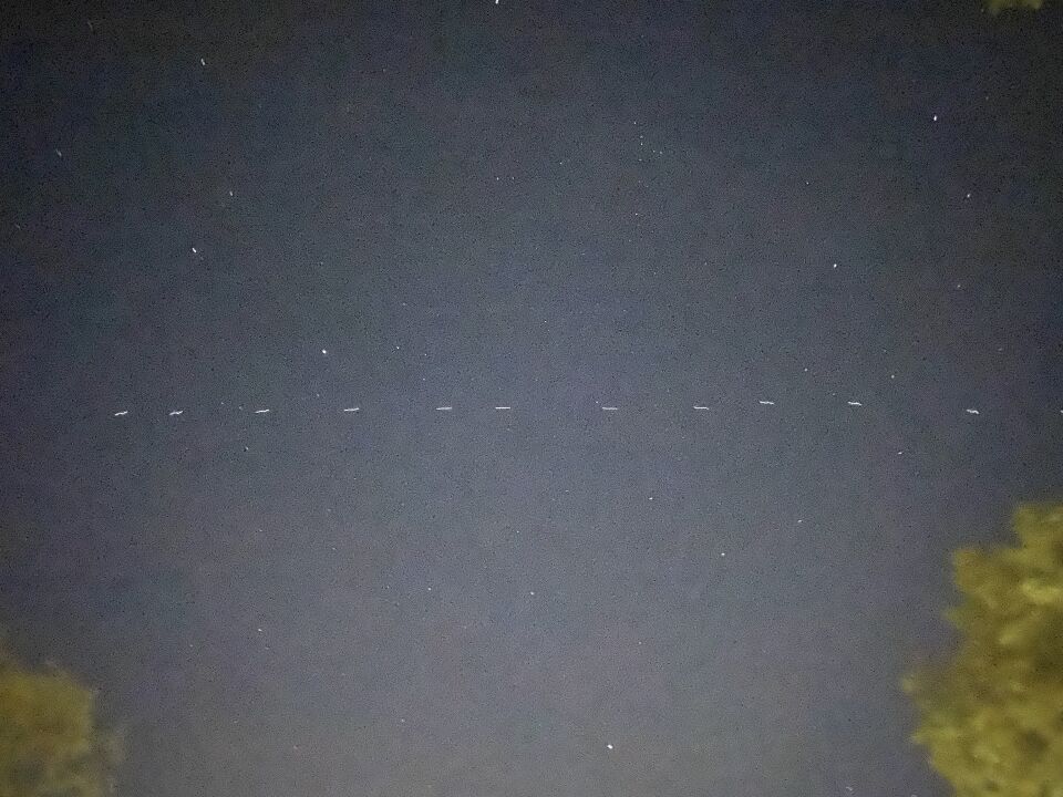 Lange formatie witte lichtjes (70+), ze vliegen richting het Noorden. foto
