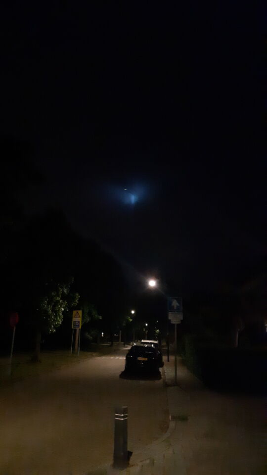 Groot verticaal lichtgevend blauw object met kleine lichtgevende bal foto