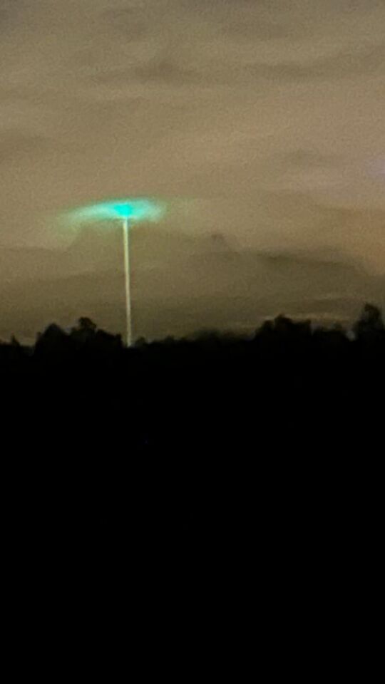 Groen bol achtig object met mist waas er omheen en lichtstraal naar aarde foto