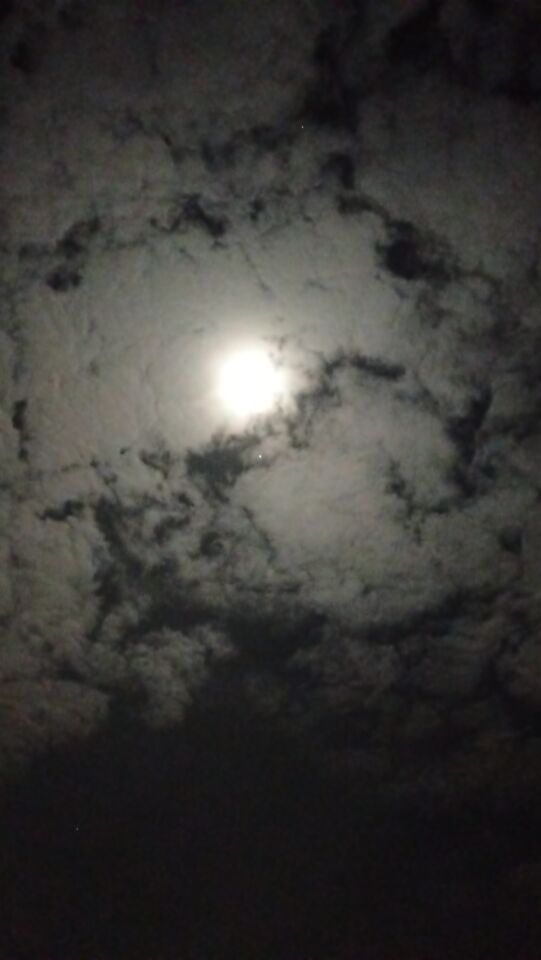 Licht punt rond volle maan voor de wolken die hoog stonden foto