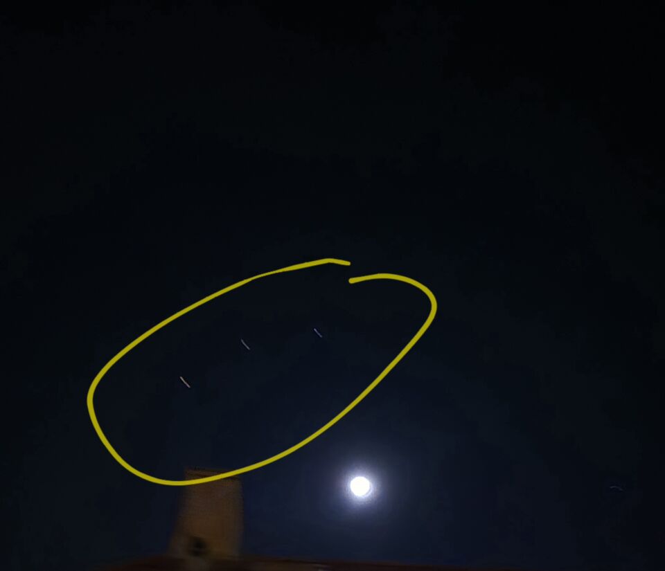 Een object dat voor de maand hangt en 3 andere objecten in de lucht foto