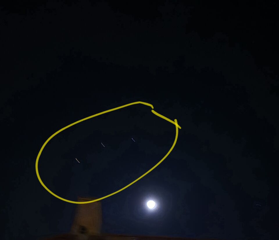 Een object dat voor de maand hangt en 3 andere objecten in de lucht foto