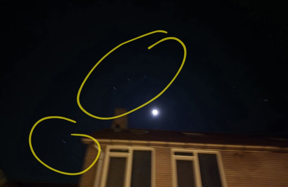 Een object dat voor de maand hangt en 3 andere objecten in de lucht foto