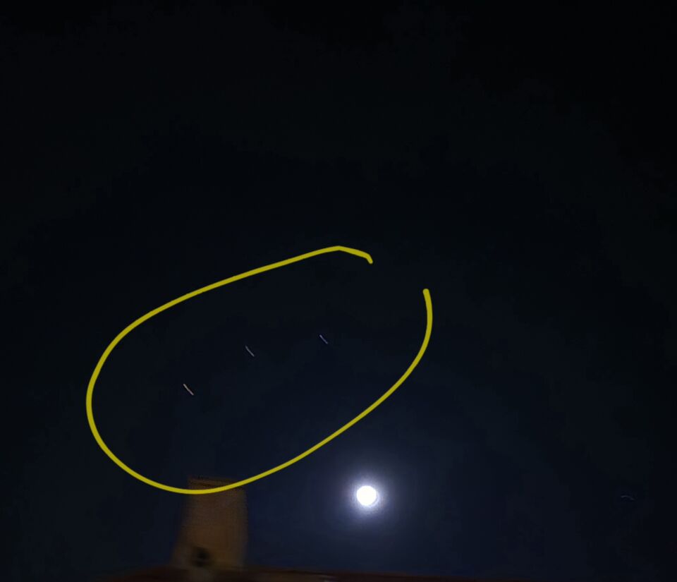 Een object dat voor de maand hangt en 3 andere objecten in de lucht foto