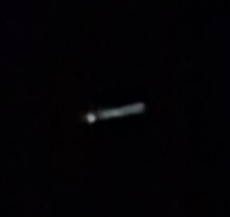 Lichtgevende sigaar vormige UFO. 1 punt ervoor maar wel verbonden met elkaar. foto