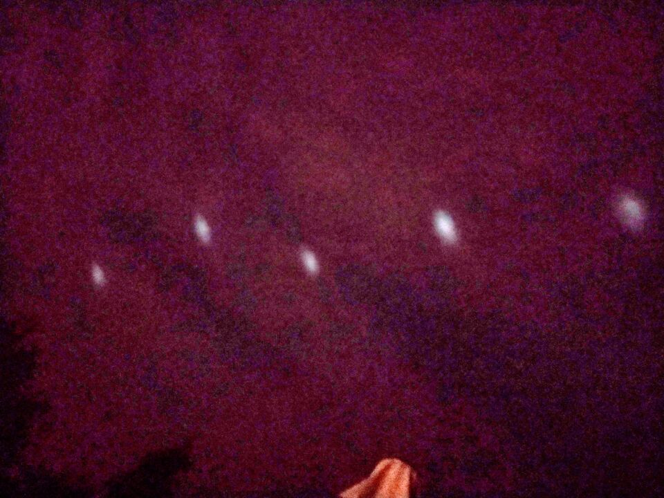 Rij van lichte bollen tegen wolkendek, hoog aan de hemel foto