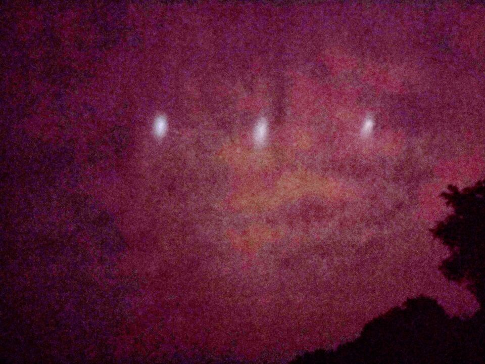 Rij van lichte bollen tegen wolkendek, hoog aan de hemel foto