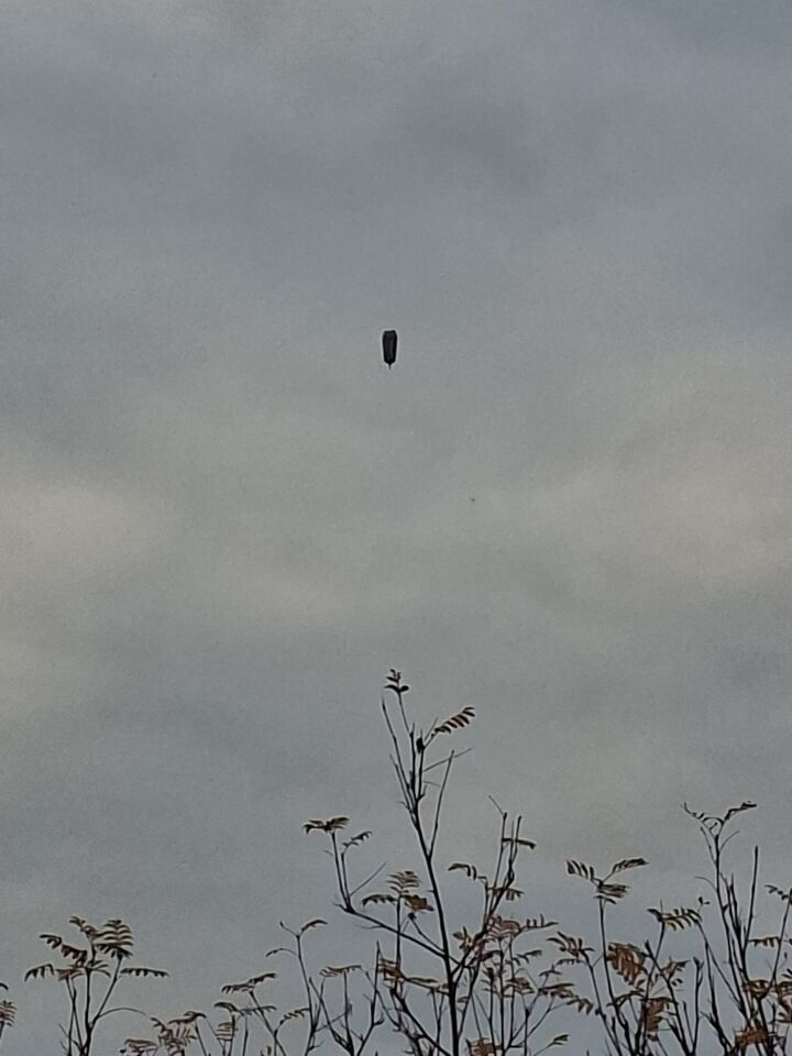 Donkere rechthoek zwevend door de lucht. Bovenop wat uitsteeksels. foto