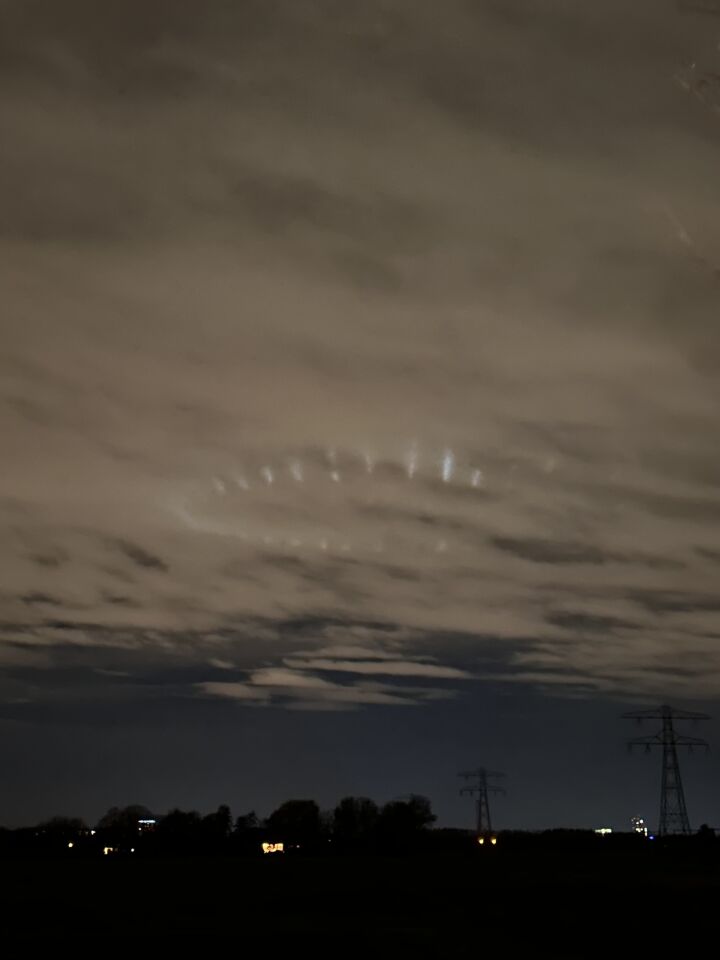 Ronde vorm met lichtpunten boven wolken, lichtstralen die omhoog reflecteren foto