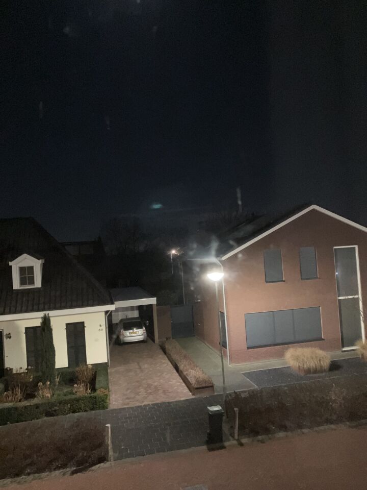 N bolvormig opject met groene verlichting en wazige menssen in de verte foto
