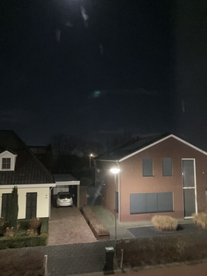 N bolvormig opject met groene verlichting en wazige menssen in de verte foto