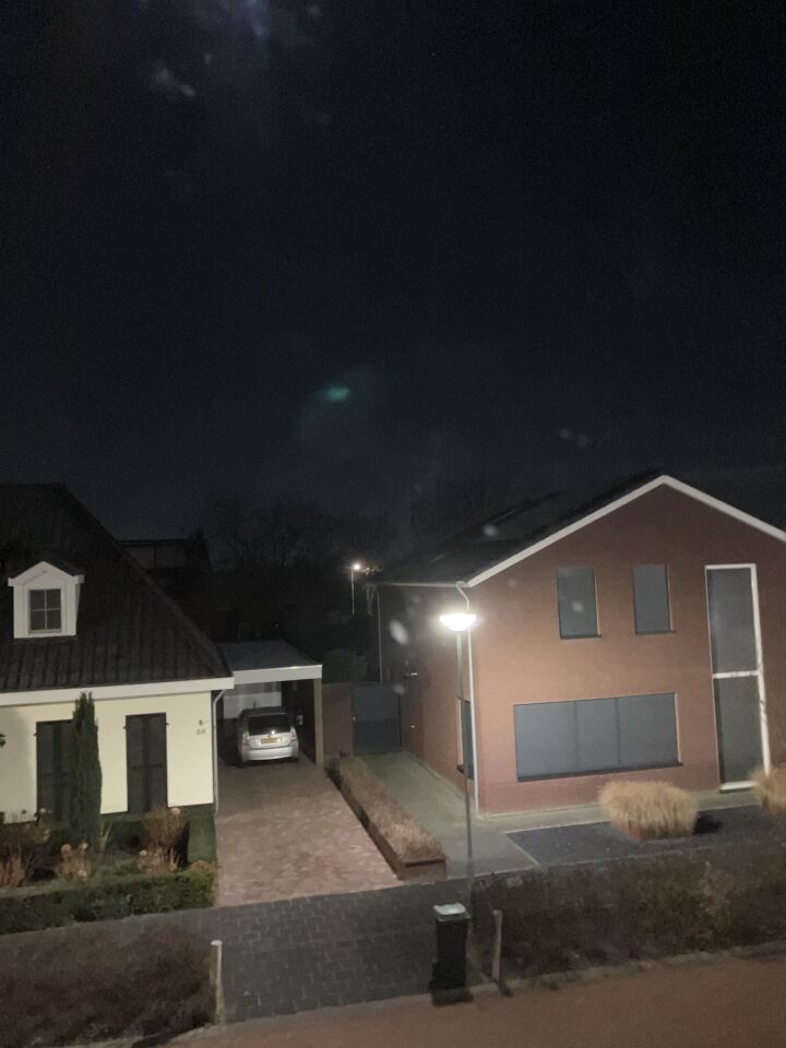 N bolvormig opject met groene verlichting en wazige menssen in de verte foto