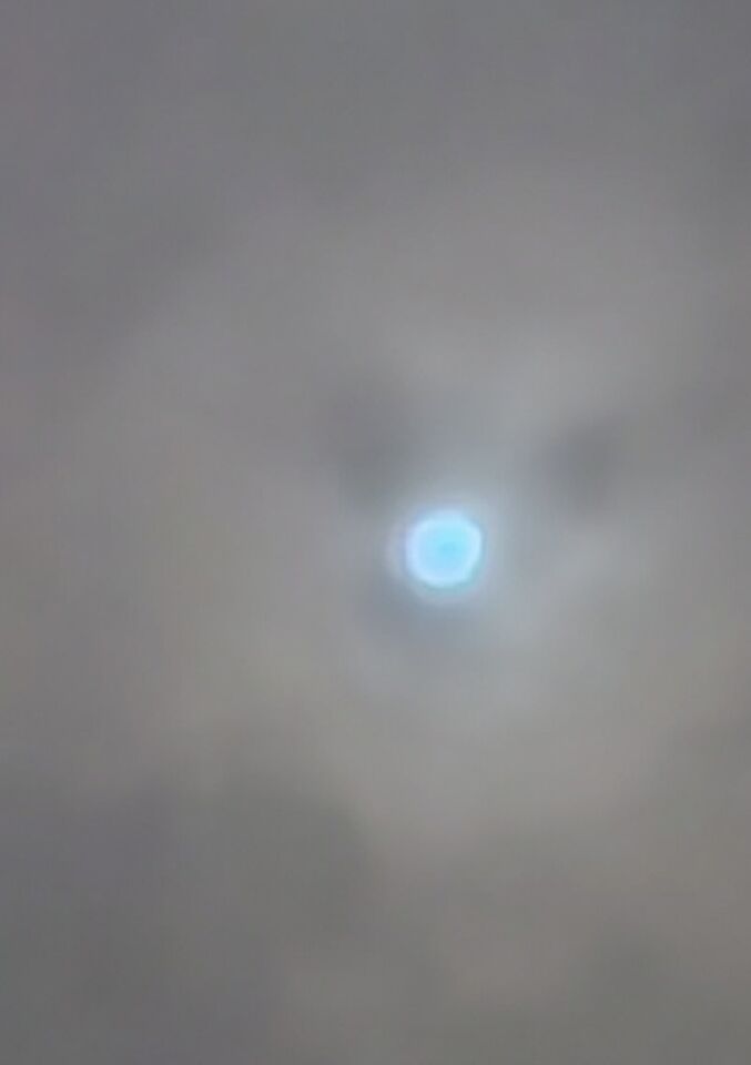 Blauwe neon achtige bol die door wolken schijnt foto