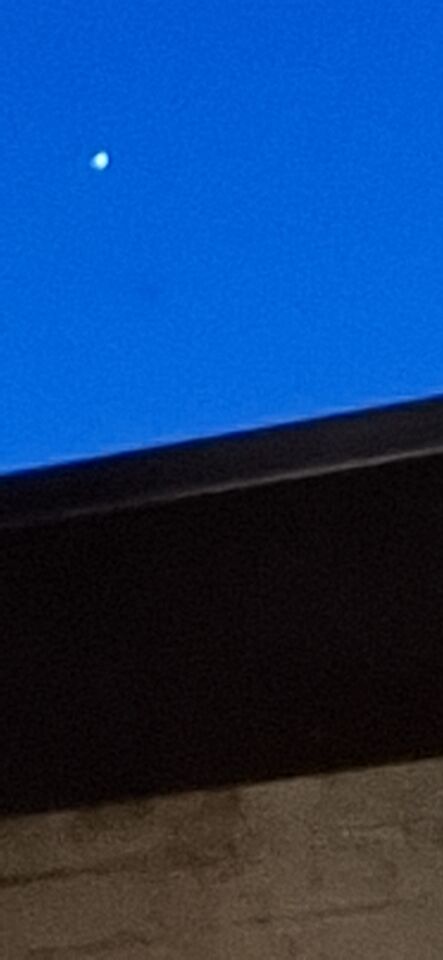 Fel wit licht 3 puntig stervormig hangt stil in de lucht boven Beverwijk foto