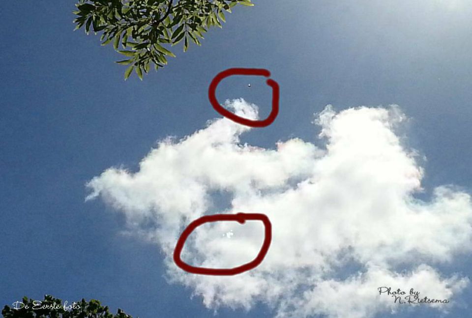 Zwart object hoog in de lucht en witte vlekken in de wolken foto
