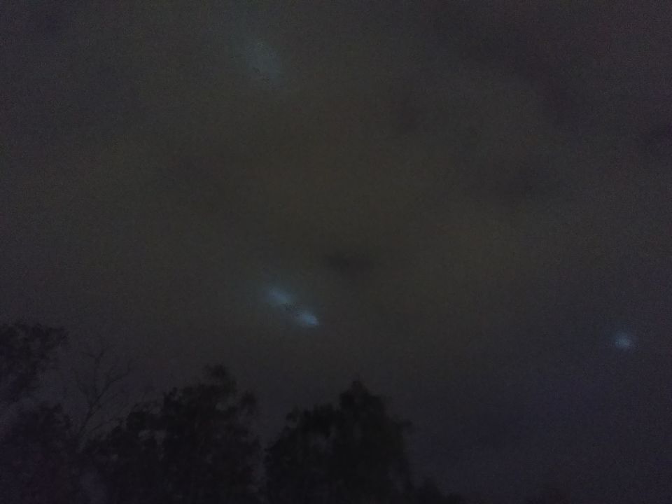 5 lichtbollen schijnen door de wolken heen ze zijn steeds in beweging wit licht foto